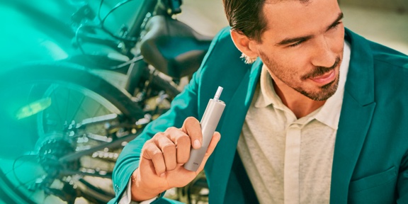 A man holding an IQOS ILUMA ONE device.