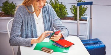 Blond woman checking her phone with a IQOS device on the table and a handbag next to her