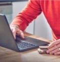 A person  types on a keyboard while holding an IQOS device. 