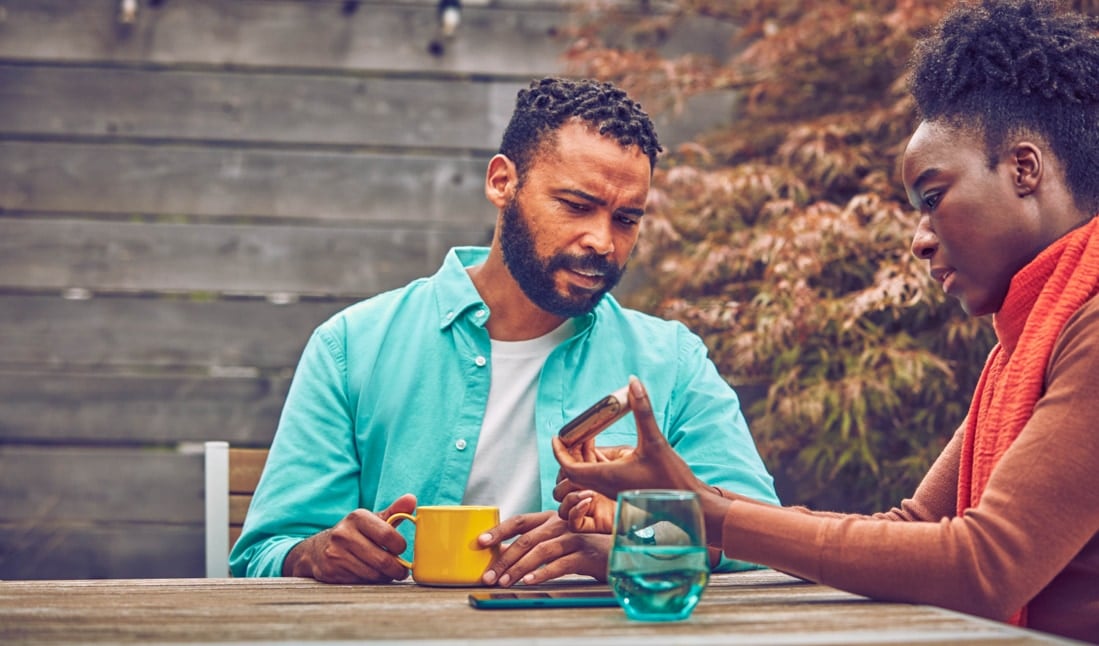 A woman and a man talking and looking at her gold IQOS DUO