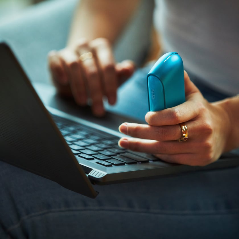 Woman holding Azure Blue IQOS ILUMA Kit.