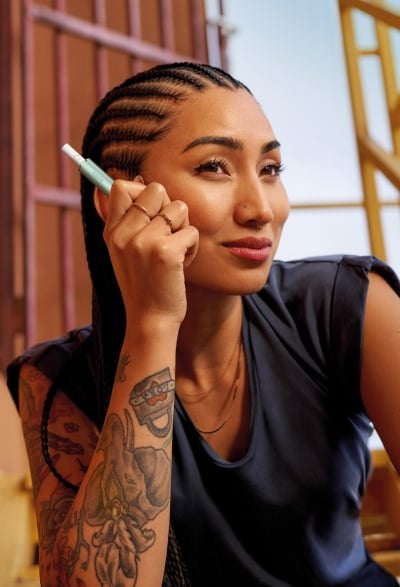 Une femme tenant un appareil IQOS bleu dans les mains.