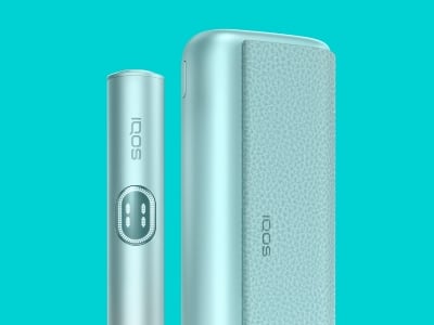 Appareil IQOS ILUMA i PRIME Breeze Blue en position droite près de son chargeur