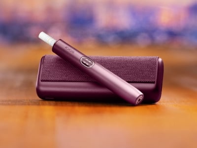 Garnet Red IQOS ILUMA i PRIME device above its charger