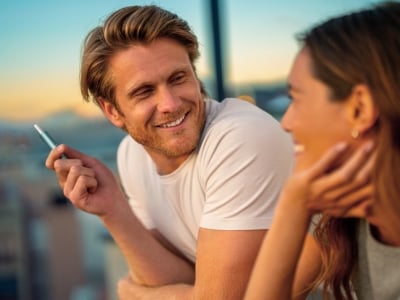 Two people smiling while holding an IQOS ILUMA i PRIME device