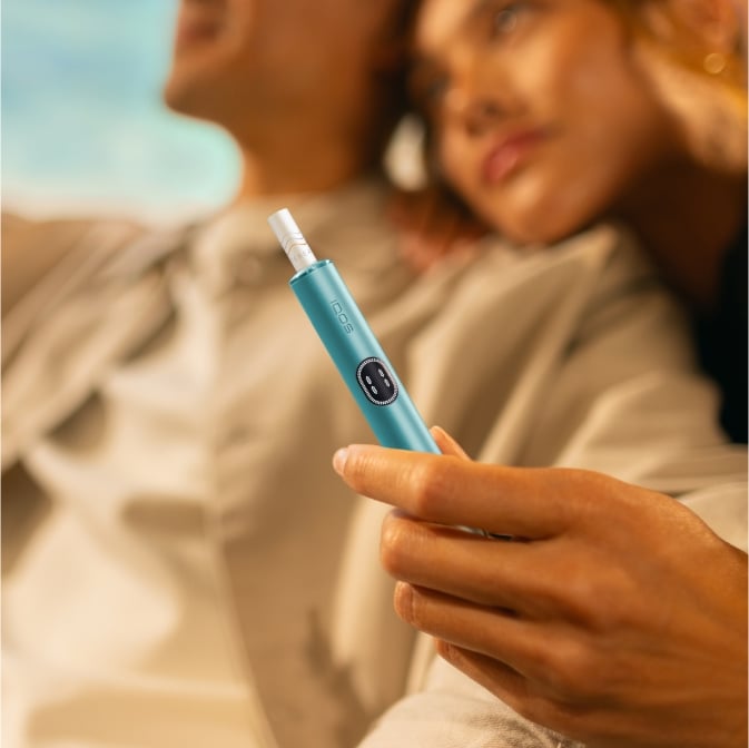 Mann und Frau, die sich umarmen und ein IQOS ILUMA i Gerät halten