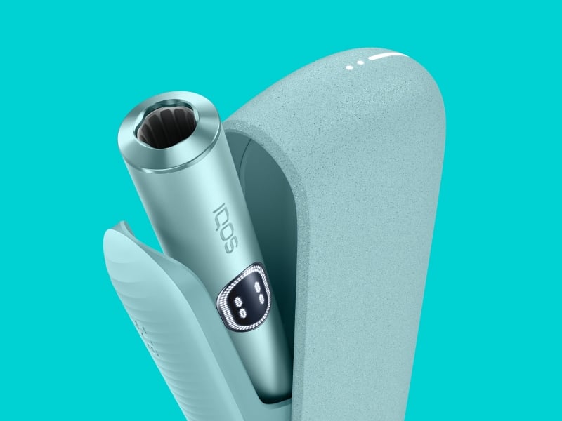 Breeze Blue IQOS ILUMA i device standing near its charger