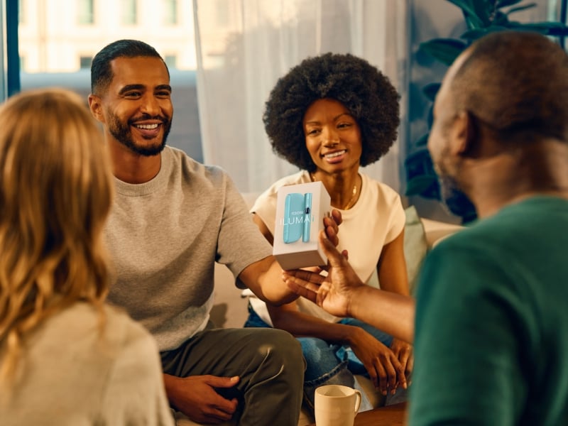 Group of people with a man showing an IQOS ILUMA i device package