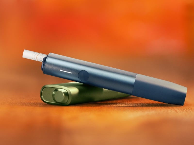 IQOS ILUMA i ONE Blue au-dessus d’un IQOS ILUMA i ONE Green, sur un fond orange