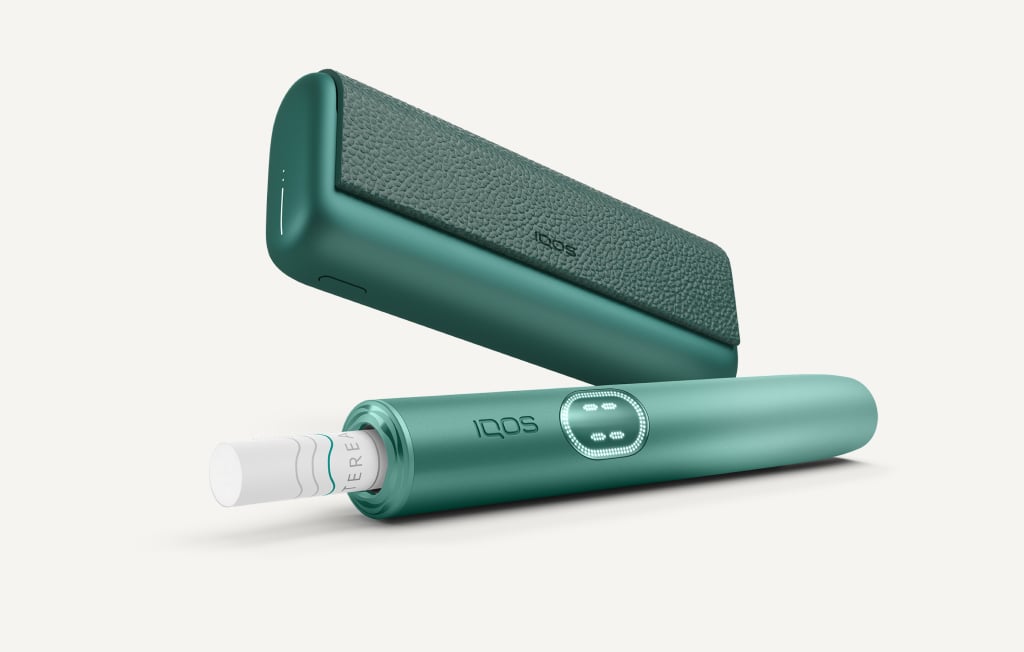 Aspen Green IQOS ILUMA i PRIME device below its charger
