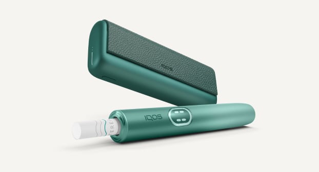 Aspen Green IQOS ILUMA i PRIME device below its charger