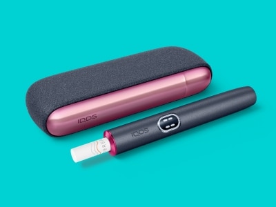 Appareil IQOS ILUMA i près de son chargeur, avec une bague et une Door Cover personnalisées