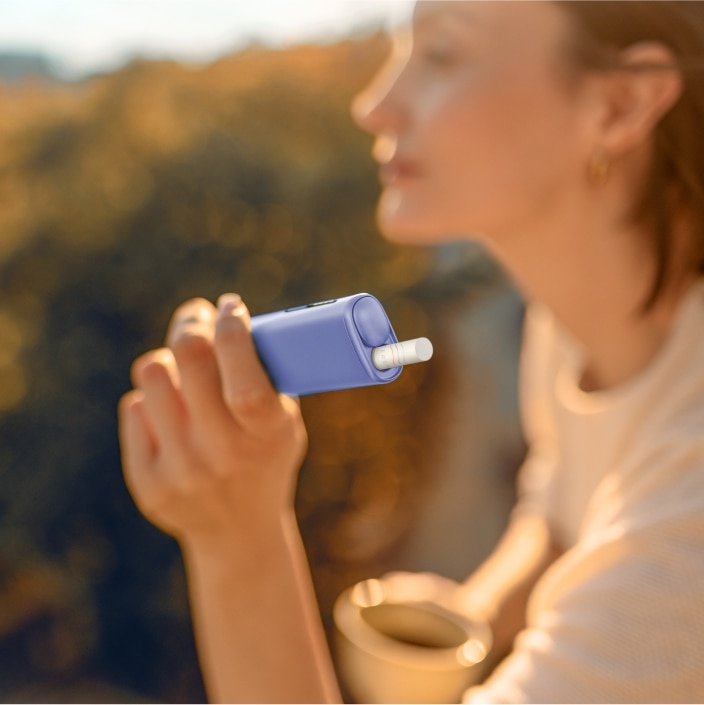 Frau hält ein  IQOS ILUMA Gerät