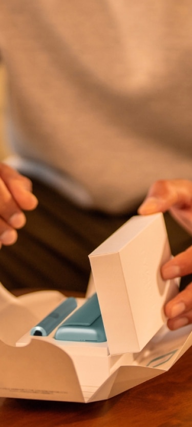 Hände, die ein IQOS ILUMA i PRIME Gerät auspacken