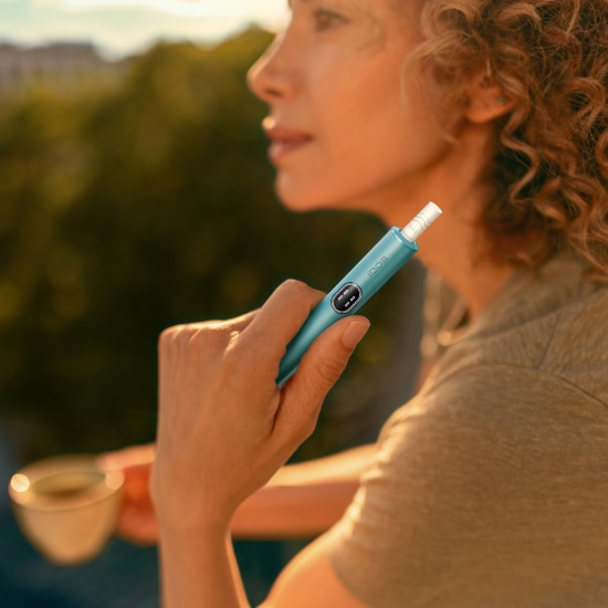 Woman holding a blue IQOS ILUMA i device