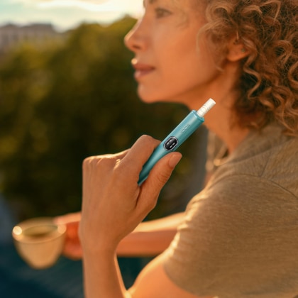 Donna con in mano un dispositivo IQOS ILUMA i Blue
