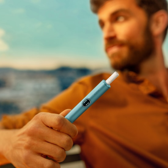 Uomo con in mano un dispositivo IQOS ILUMA i Blue