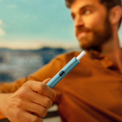Mann hält ein blue IQOS ILUMA i Gerät