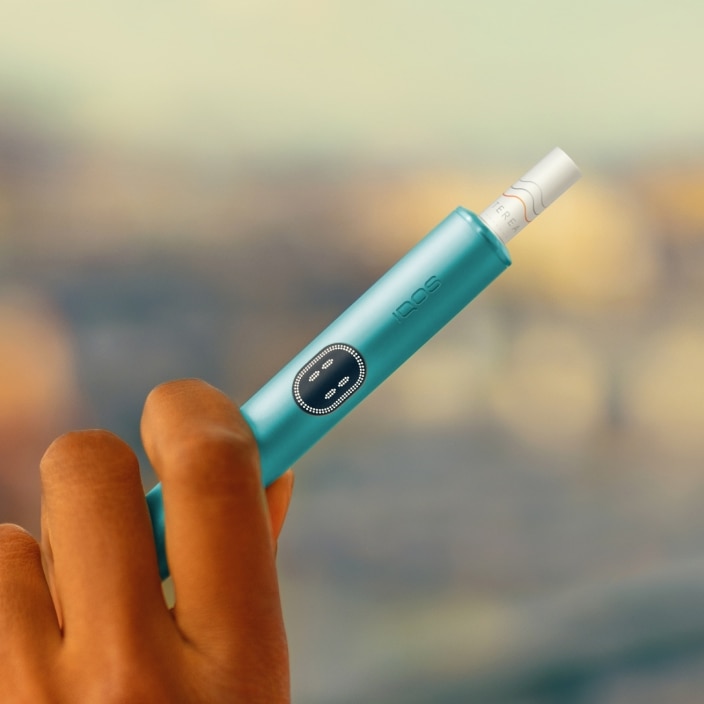 Detail einer Hand, die ein blue IQOS ILUMA i Gerät hält