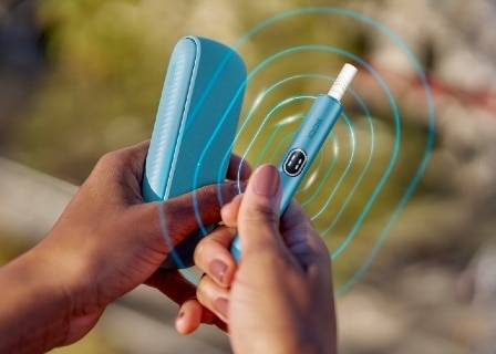 Detail einer Hand, die ein blue IQOS ILUMA i Gerät hält