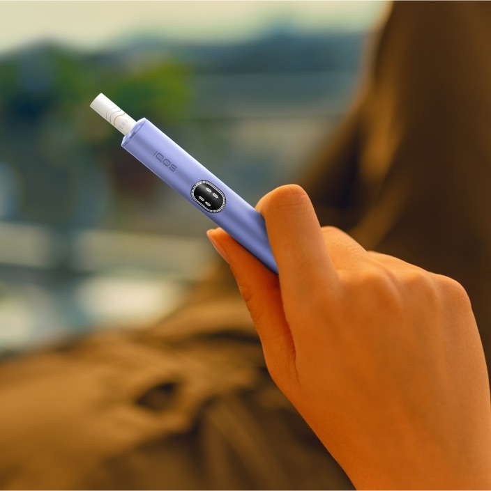 Dettaglio di una mano che tiene un dispositivo IQOS ILUMA i violet