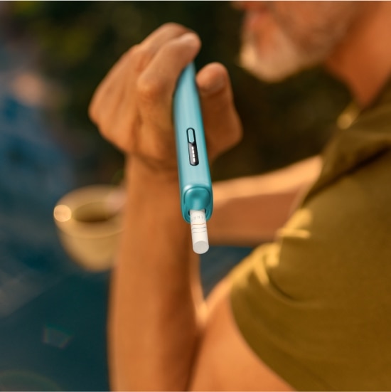 Vue détaillée d’une main tenant un appareil IQOS ILUMA i Blue