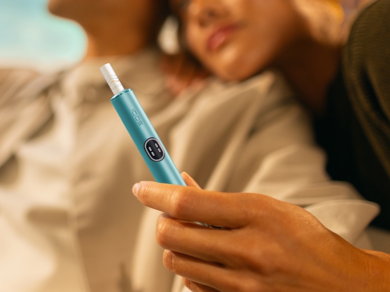 Mann und Frau, die sich umarmen und ein IQOS ILUMA i Gerät halten