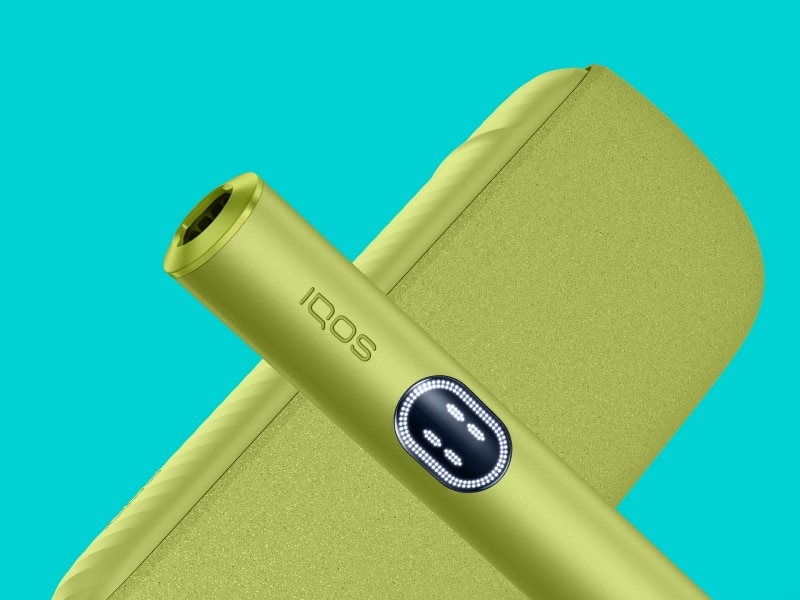 Dispositivo IQOS ILUMA i Green posto davanti al relativo Pocket Charger