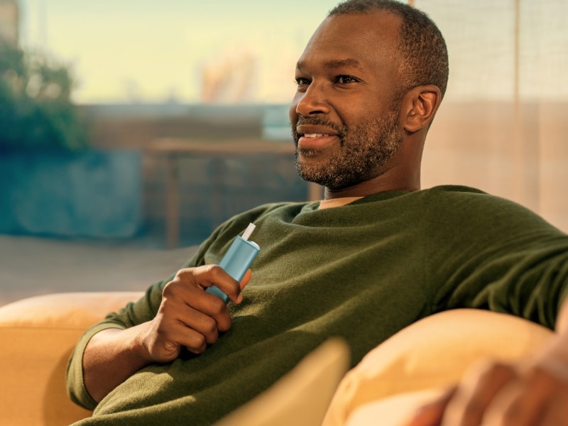 Uomo con in mano un dispositivo IQOS ILUMA i ONE