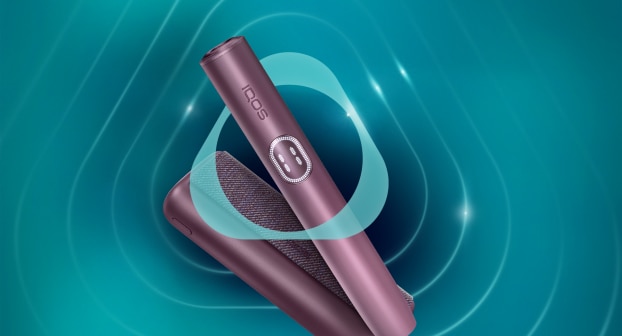 Appareil IQOS ILUMA i PRIME Garnet Red et son chargeur sur fond turquoise foncé