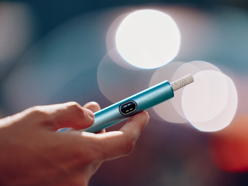 Hand hält einen blauen IQOS ILUMA i Holder