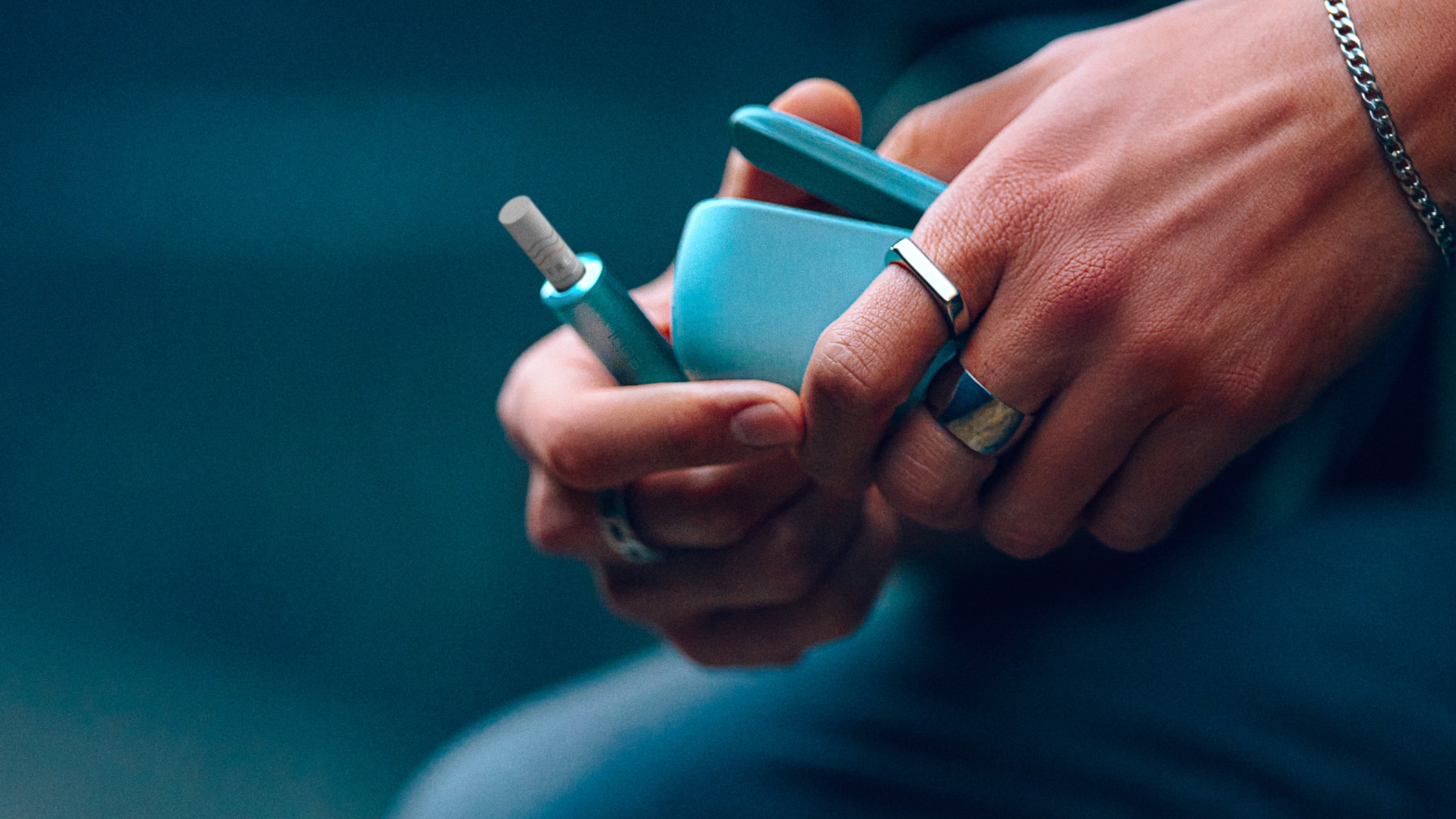Une main tenant un IQOS ILUMA i Breeze Blue
