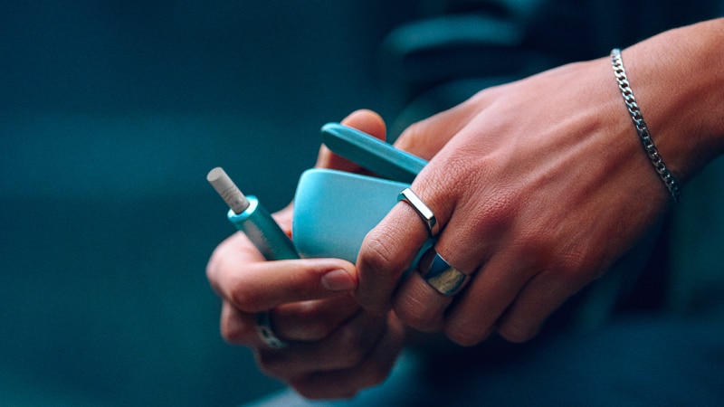 Hand holding a blue IQOS ILUMA i Breeze Blue
