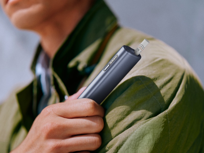 A man holding IQOS ILUMA i ONE